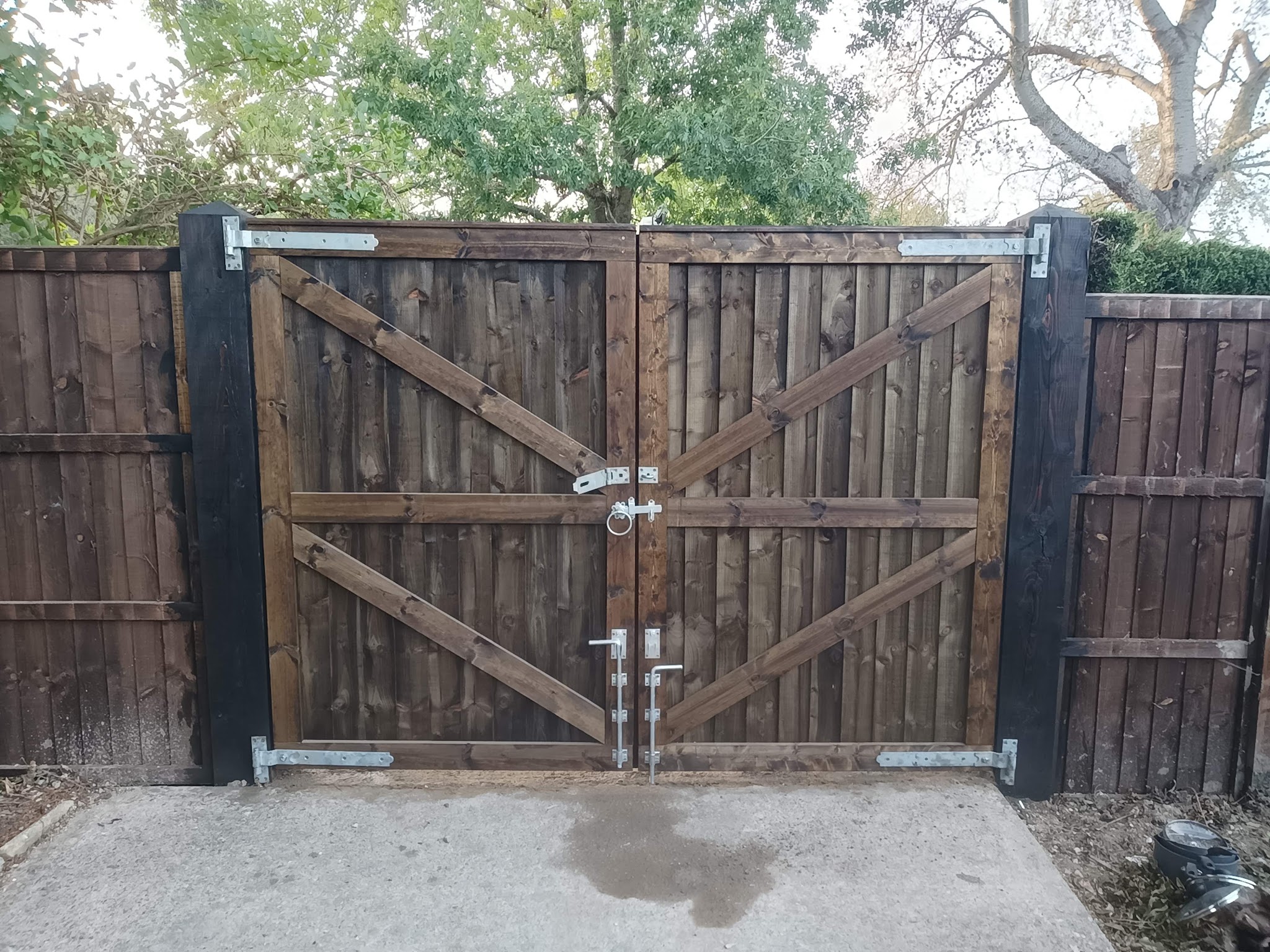 A pair of timber ledged and braced gates hung on black posts