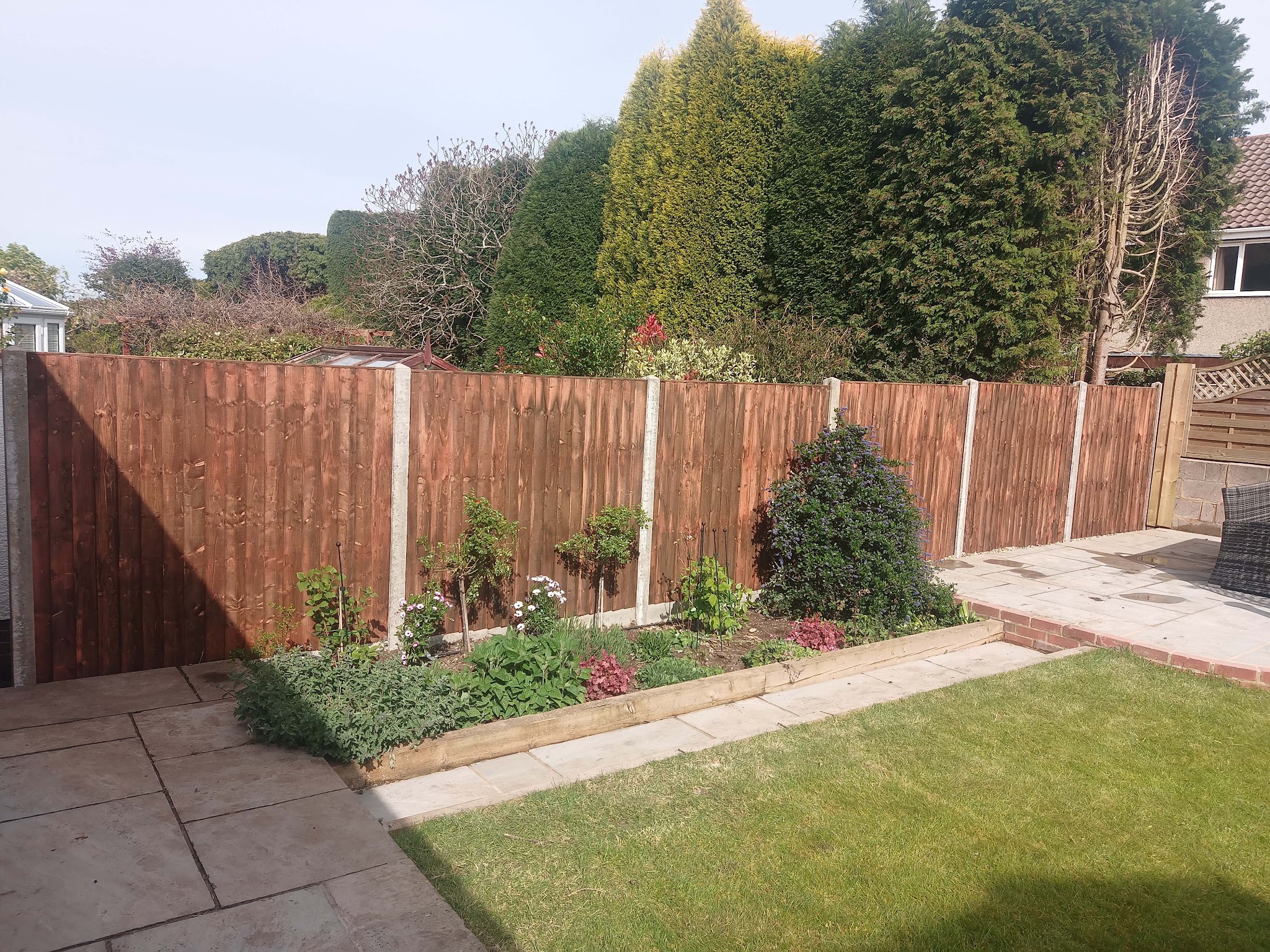 A lawn edged by a sleeper-built planted border and new closeboard fencing