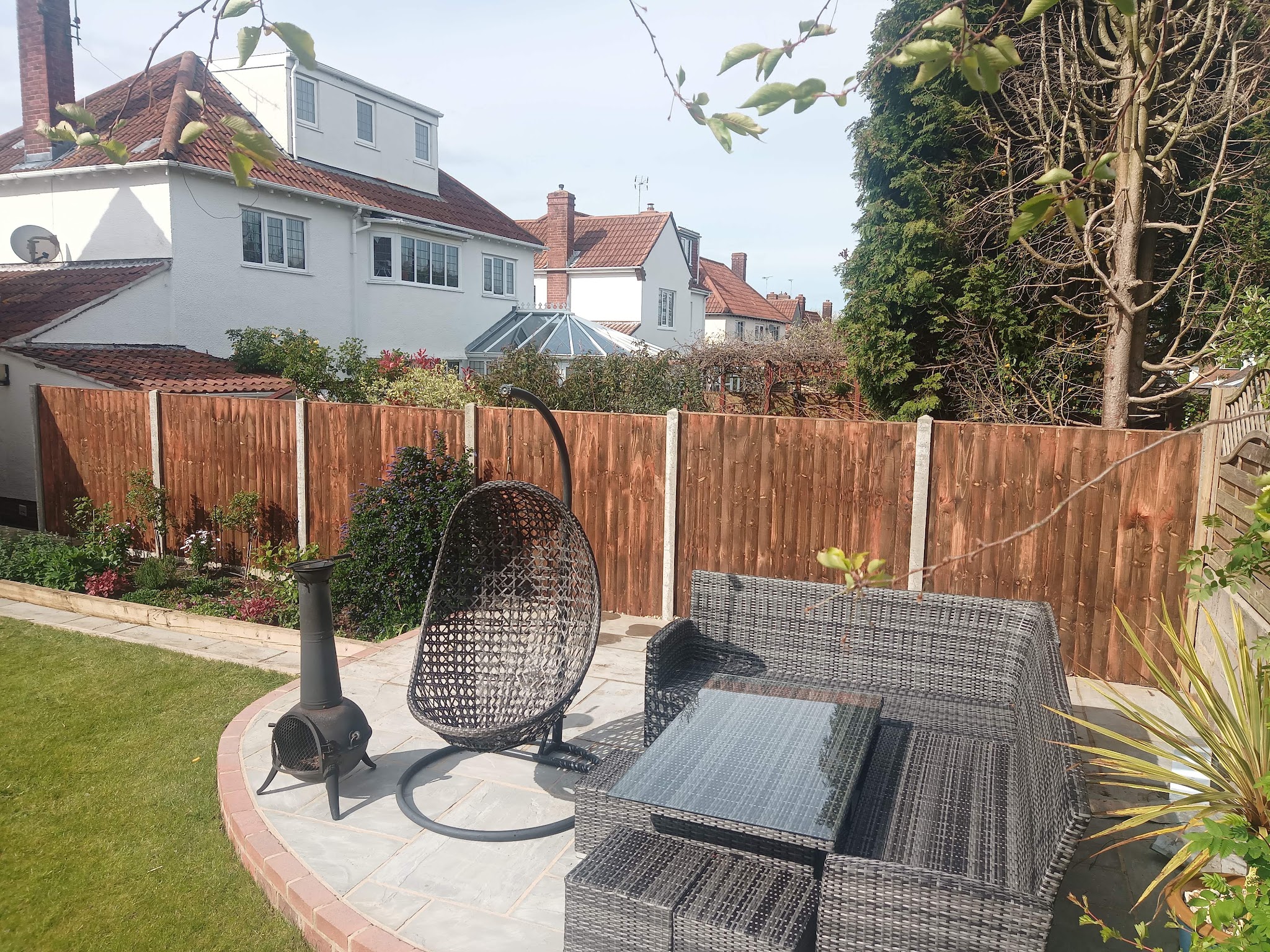 A finished garden by Milo Landscapes & Fencing: patio with a curved brick edge, new lawn and closeboard fencing